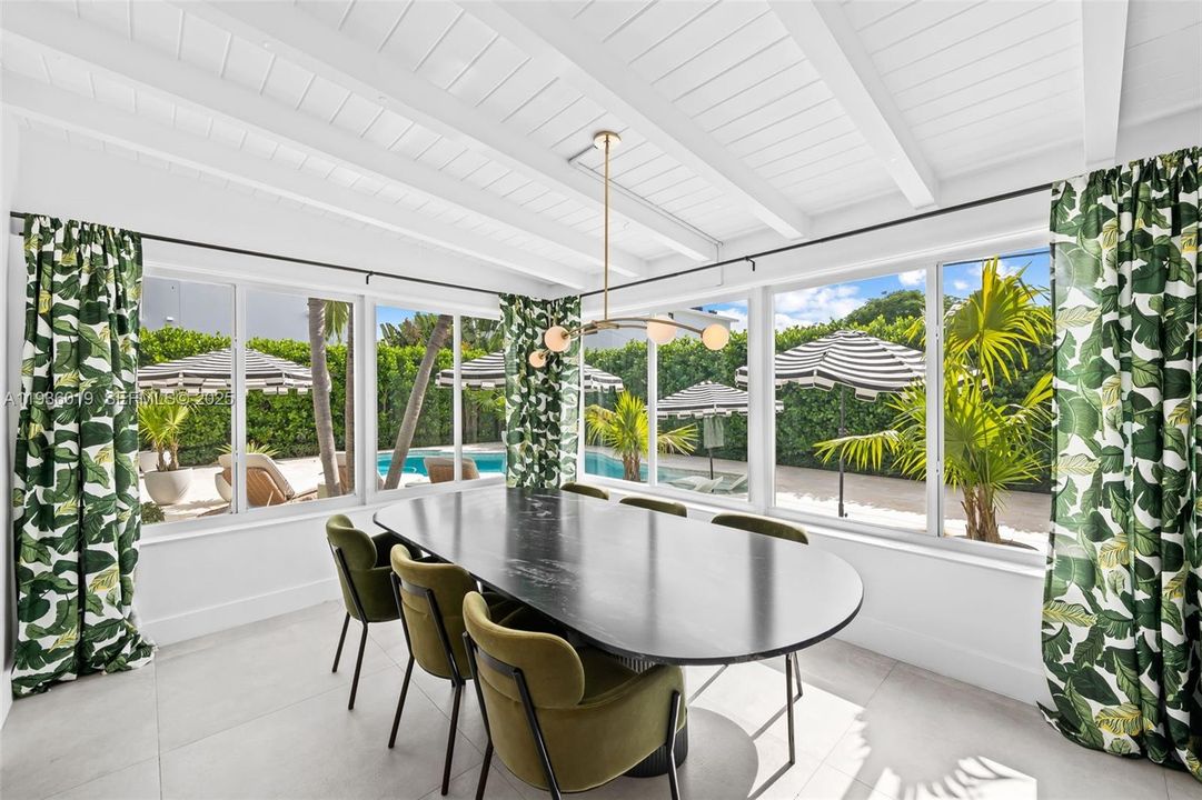 Sunlit formal dining with pool and outdoor oasis views.