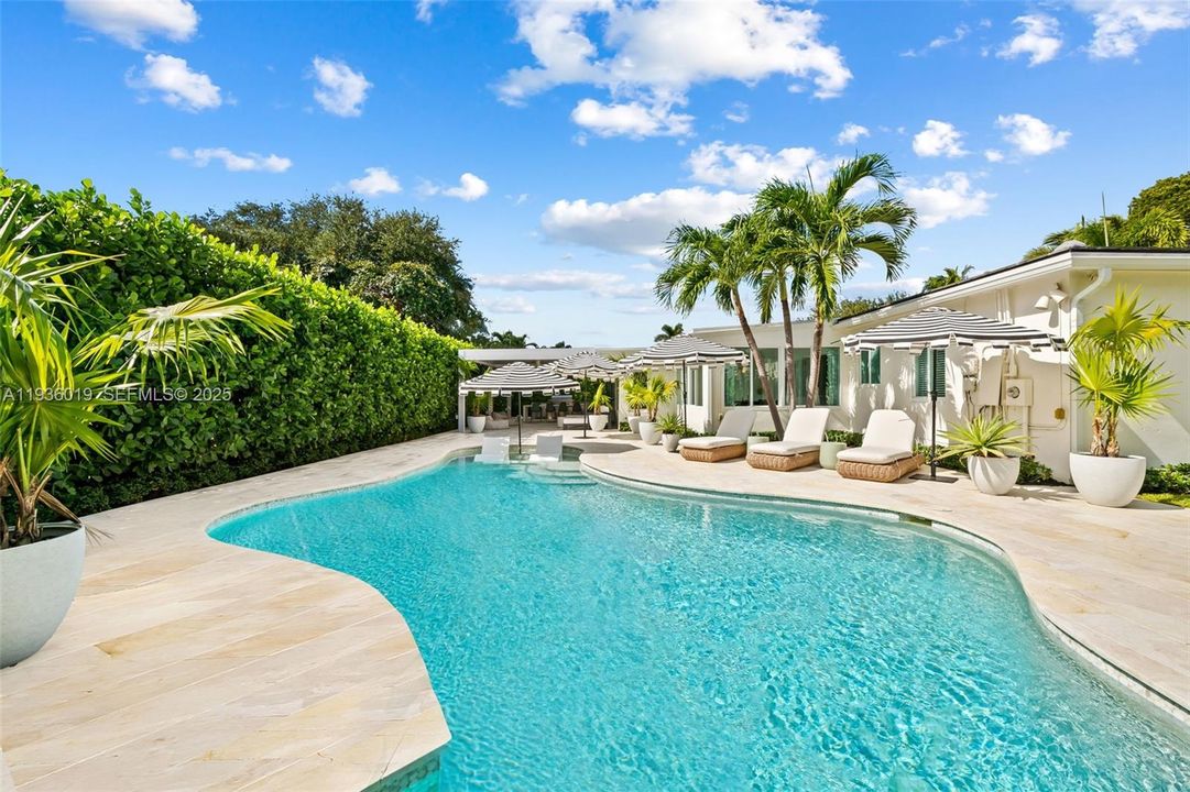 Outdoor oasis featuring view to summer kitchen, covered lounge area & side yard.