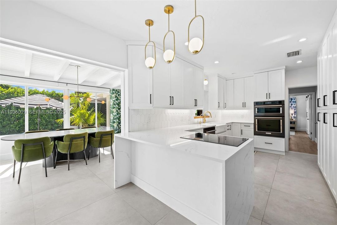 Custom kitchen featuring breakfast bar with view to formal dining and pool area.