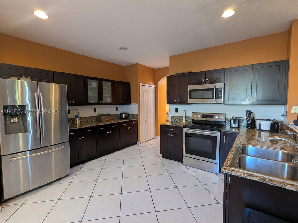 Modern kitchen featuring stainless steel appliances, dark wood cabinetry, and granite countertops