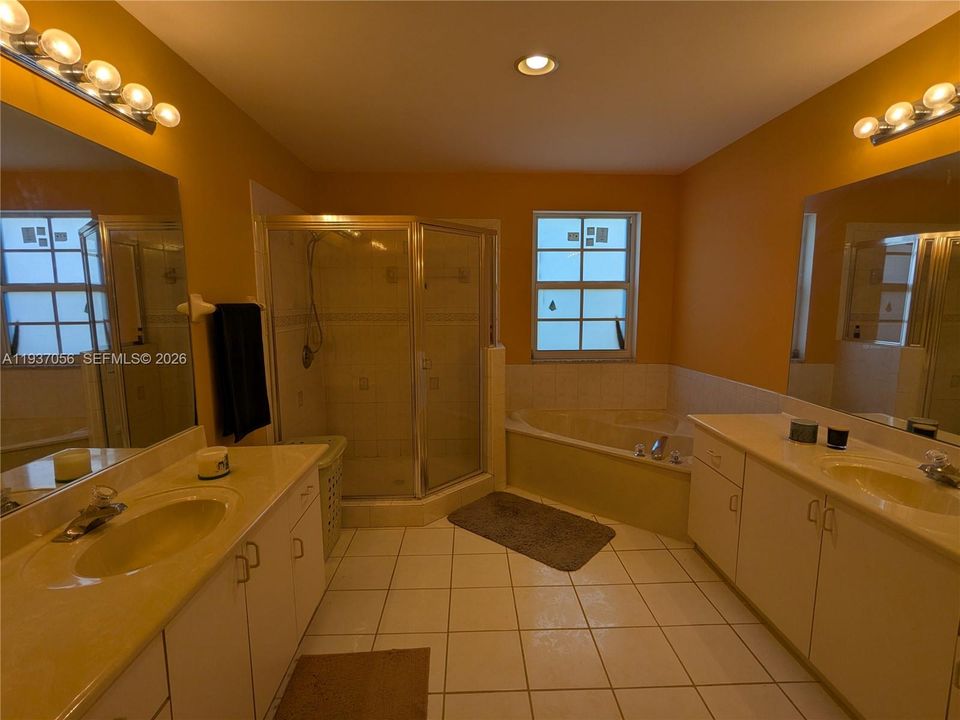 Spacious primary bathroom with double vanities and separate glass shower