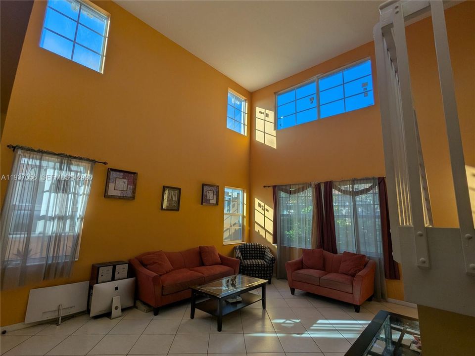 Bright and airy living room with impressive high ceilings and expansive Impact windows