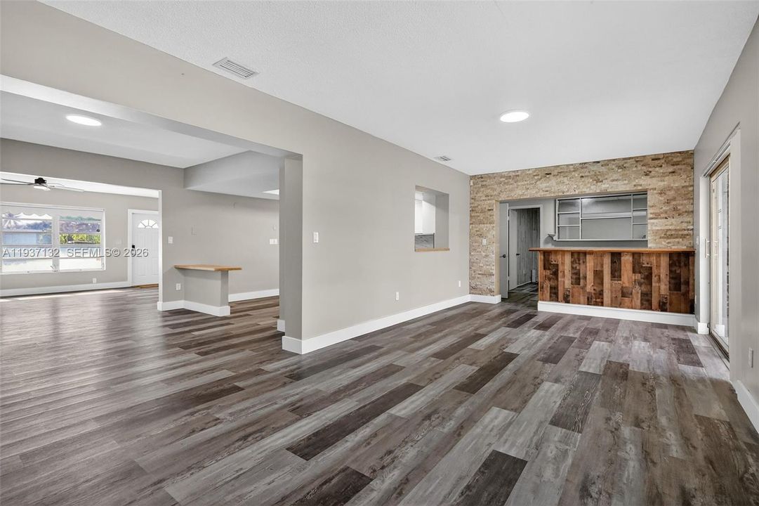 2ND LIVING ROOM, BUILT IN BAR, BACKDOOR TO POOL AND DEN ROOM IN THE BACKGROUND