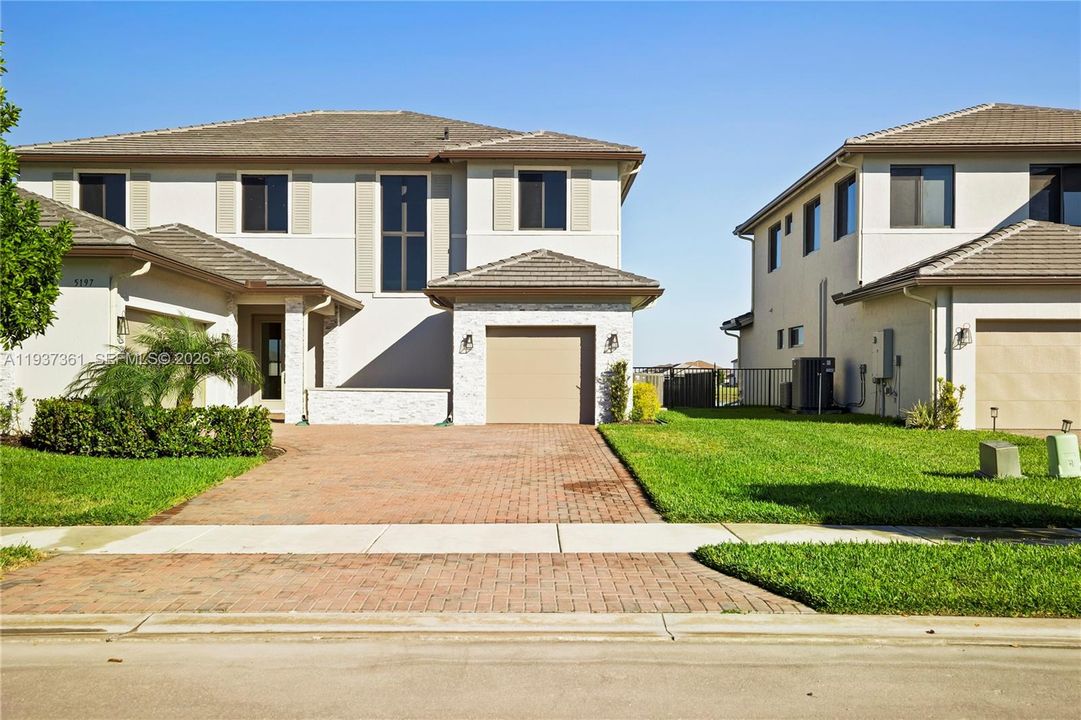 Front exterior with paver driveway and three-car garage