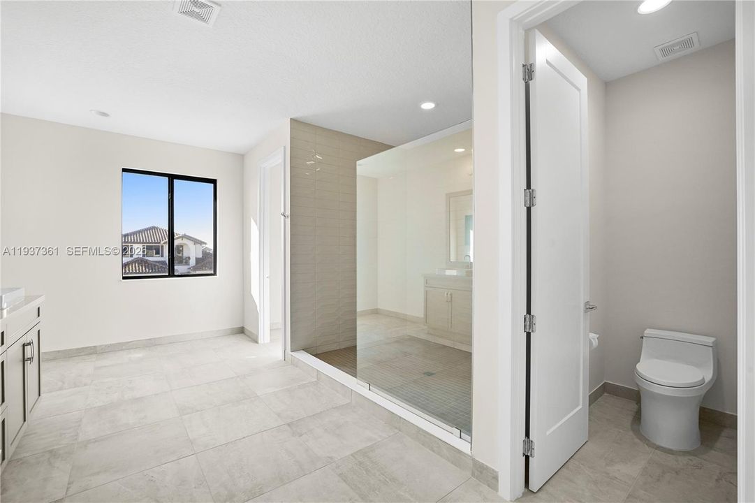 Alternate view of the primary bathroom showcasing dual water closets