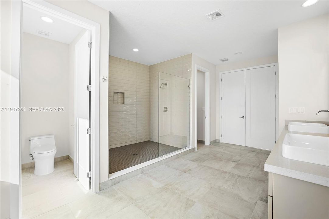 Primary bathroom featuring dual private water closets and walk-in shower