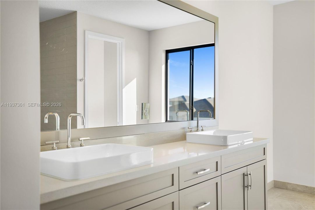 Primary bathroom featuring dual vanities and quartz detailing