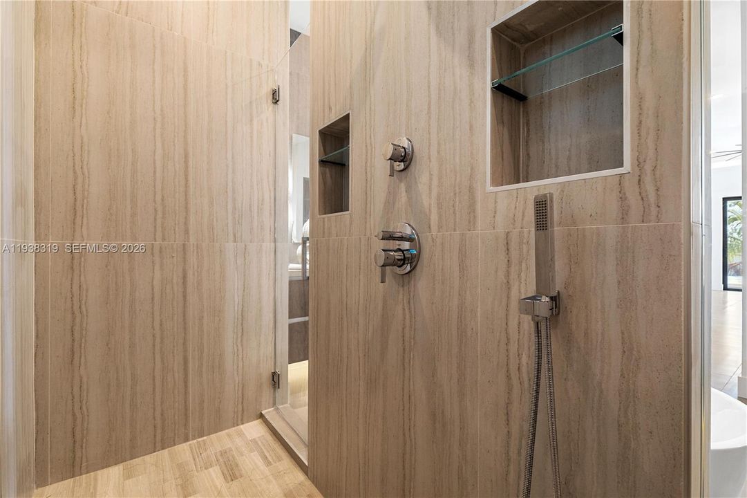 The primary bathroom features a walk-through shower equipped with multiple showerheads for a spa-like experience.
