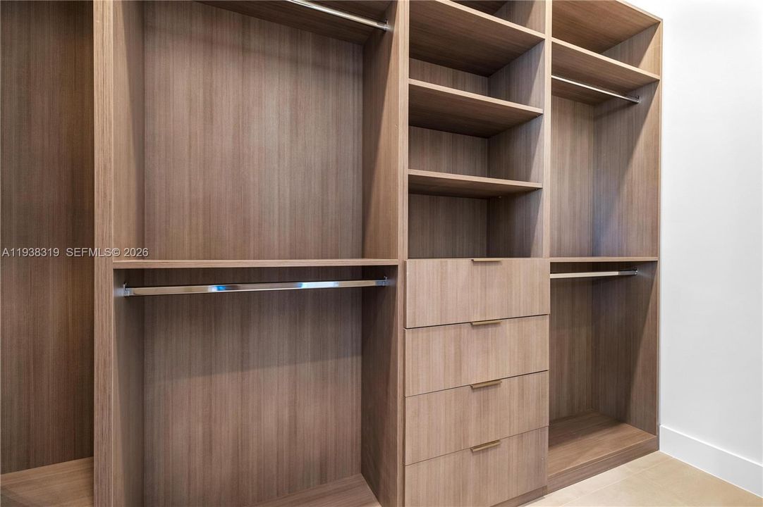 The primary suite includes his-and-hers closets with custom-built cabinetry, providing ample organized storage and a luxurious touch.