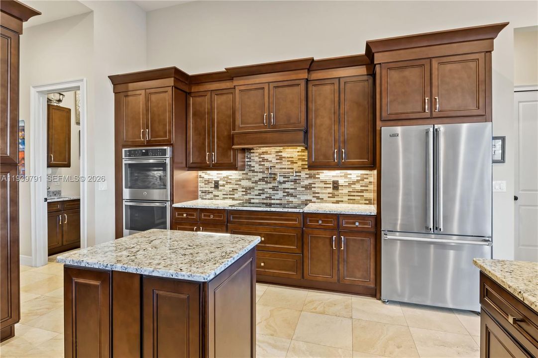 Bright, elegant kitchen featuring a double oven, rich wood cabinetry, and seamless flow to the lanai, perfect for enjoying the home’s sophisticated lifestyle.