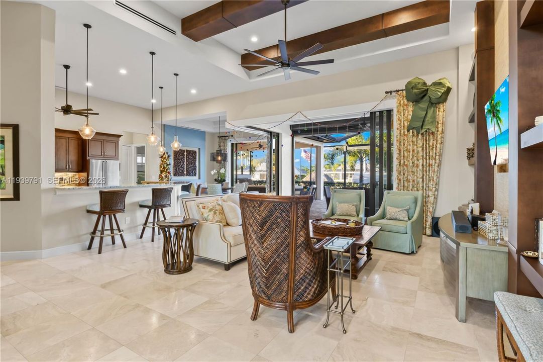 Sun-drenched living area with soaring ceilings and expansive pocketing sliders, seamlessly connecting the indoor space to the sparkling pool and canal beyond.