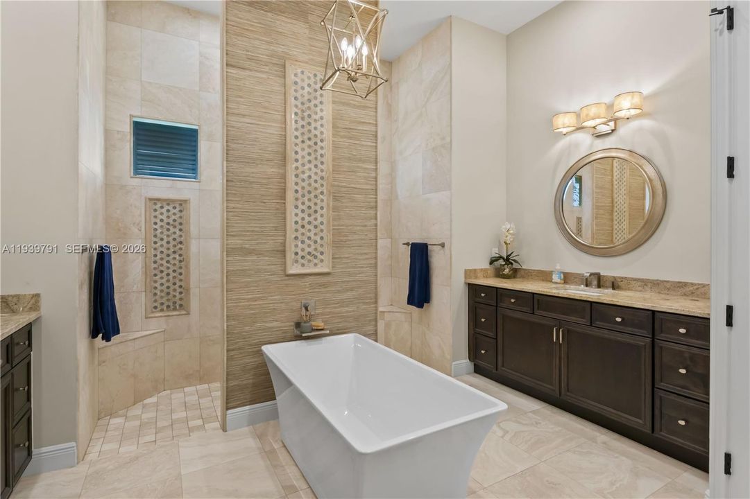 Spa-inspired bathroom with dual vanities, granite countertops, and wrap around shower, exuding sophistication.