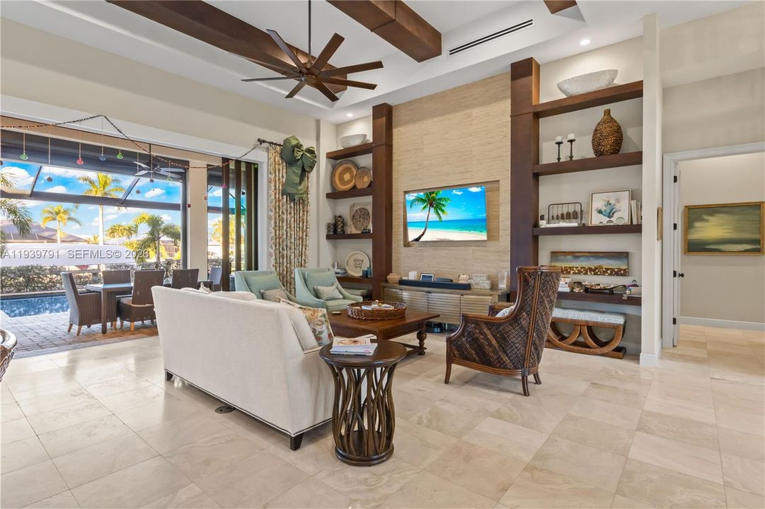 Elegant open-concept living room featuring travertine floors, natural light, and panoramic waterfront views.
