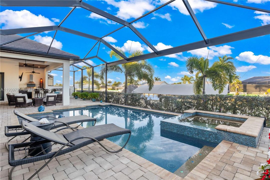 Entertainment-ready lanai featuring a complete outdoor kitchen, ample seating, and direct access to pool, spa, and sunset vistas.