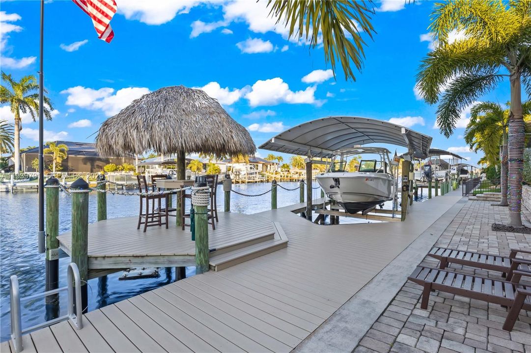 Scenic outdoor retreat featuring boat lift, tiki hut, and panoramic waterway views.