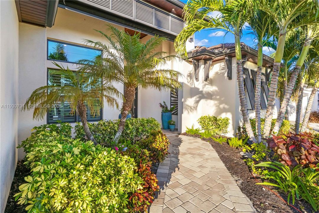 nviting front entrance framed by Bahama shutters, lush landscaping and pavered walkways, creating a welcoming first impression.