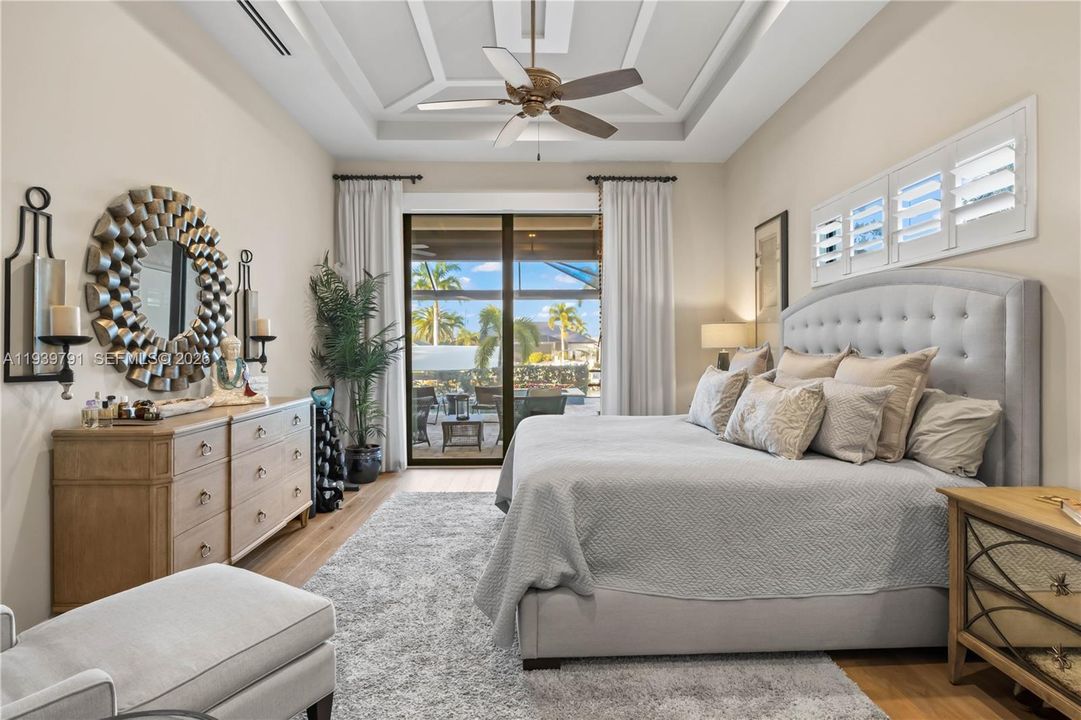 Luxurious primary suite with soaring ceilings, water views, and sliding doors to the lanai, creating a serene retreat.