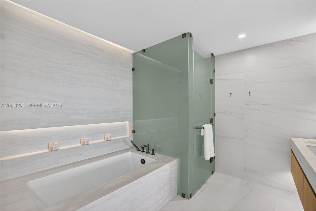 The 06 line primary bath feels like a private spa. Oversized and beautifully proportioned, it features a frameless glass walk in shower, designer soaking tub, dual vanities with stone counters, and sleek modern fixtures. Clean architectural lines, neutral luxury finishes, and generous storage for a calm, resort style retreat that complements the open coastal aesthetic of the residence.