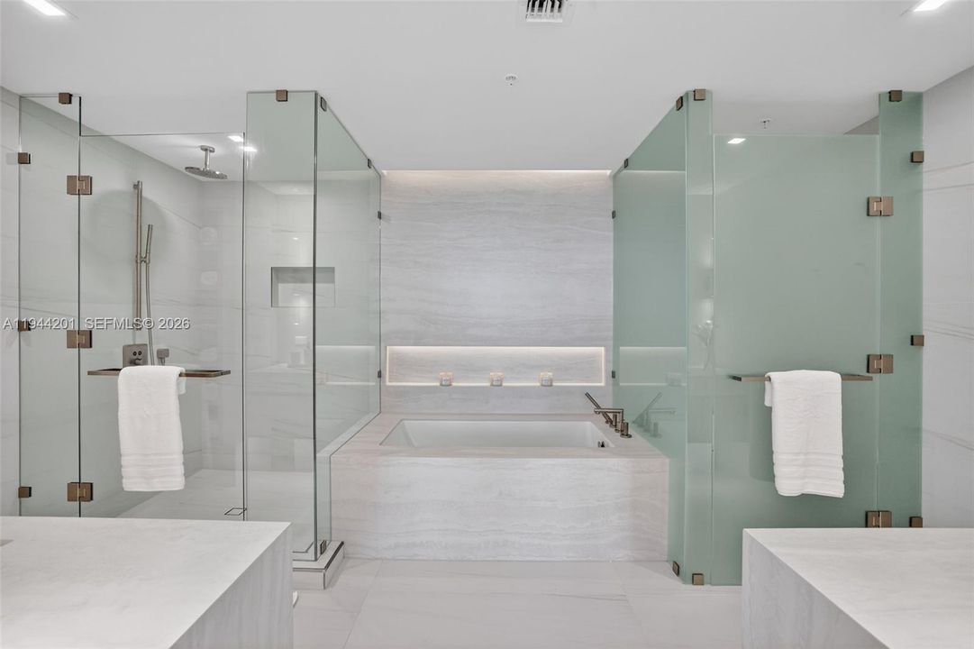 The 06 line primary bath feels like a private spa. Oversized and beautifully proportioned, it features a frameless glass walk in shower, designer soaking tub, dual vanities with stone counters, and sleek modern fixtures. Clean architectural lines, neutral luxury finishes, and generous storage for a calm, resort style retreat that complements the open coastal aesthetic of the residence.