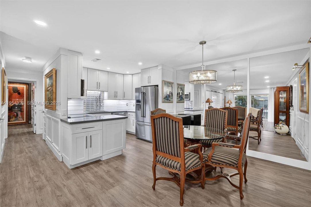 Open kitchen w/ shaker style cabinets, quartz counters and stainless appliances opens to dining area w/ framed mirrored walls bringing in even more natural light