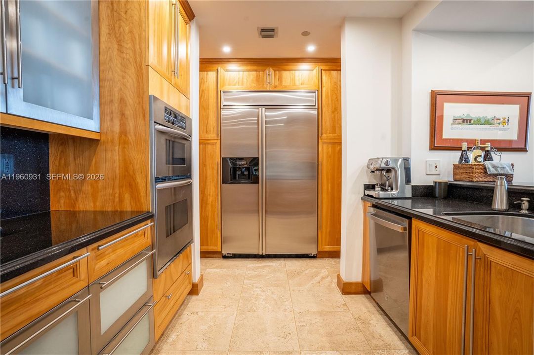 Custom-crafted wood kitchen cabinets and glass cabinets complement the black stone countertop.