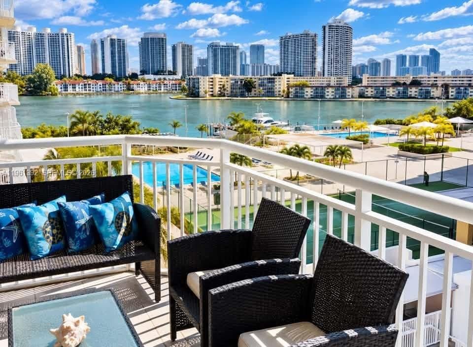 Balcony featuring white railings and water-fronting scenery with distant city skyline