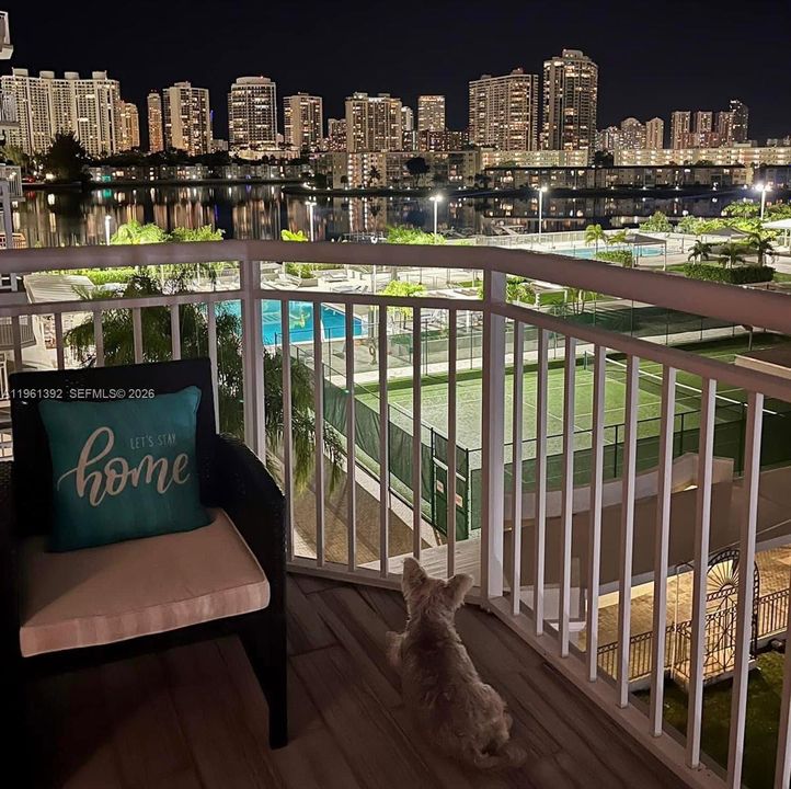 Private balcony featuring wood-finish flooring, white metal railing, and cityscape illumination