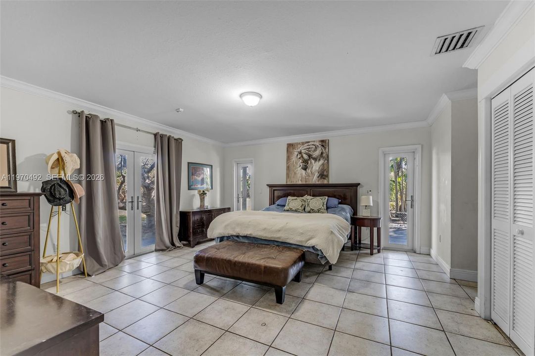 Bedroom #1 with 3 sets of doors leading to the wrap around patio w/ his-hers closets