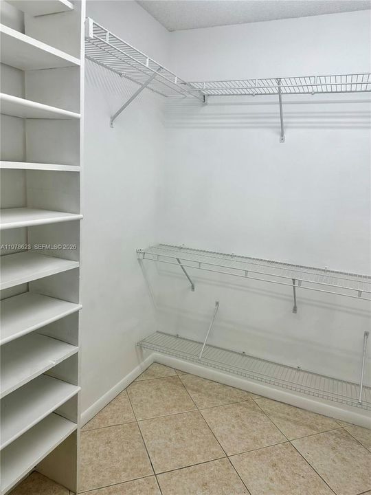 LEFT SIDE VIEW OF WALK IN CLOSET WITH PLENTY OF STORAGE TO KEEP THINGS VISIBLE