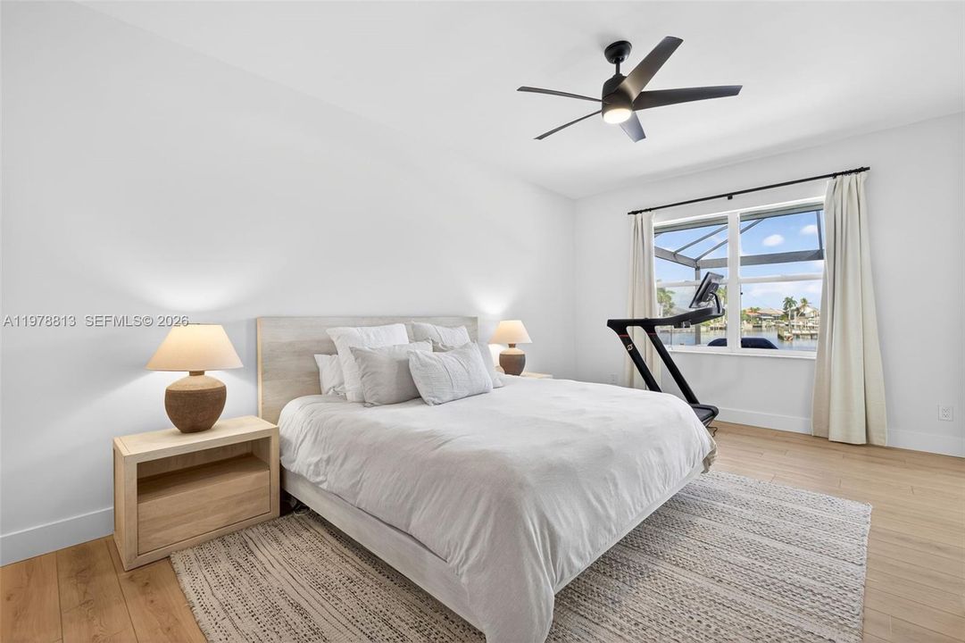 Primary bedroom featuring LVP, sleek ceiling fan, and access to pool patio