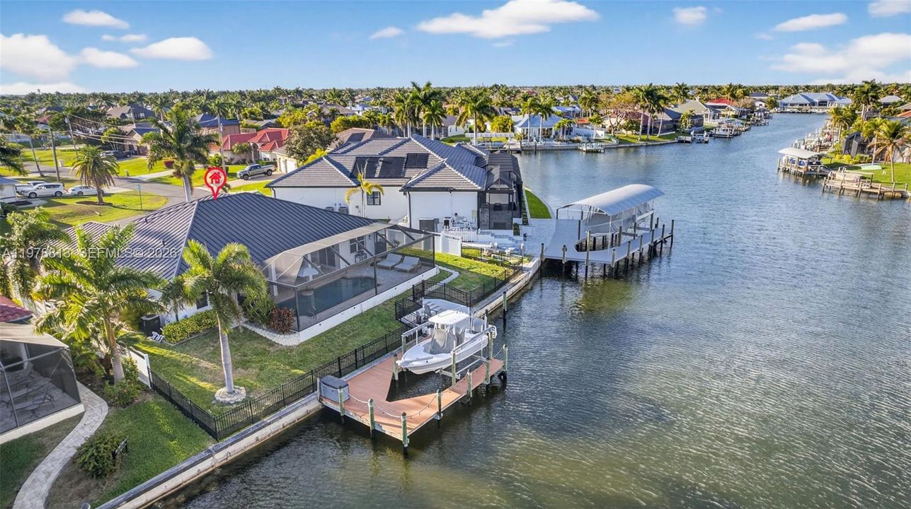 Dock area featuring a lanai, a large water view, boat lift, & residential view