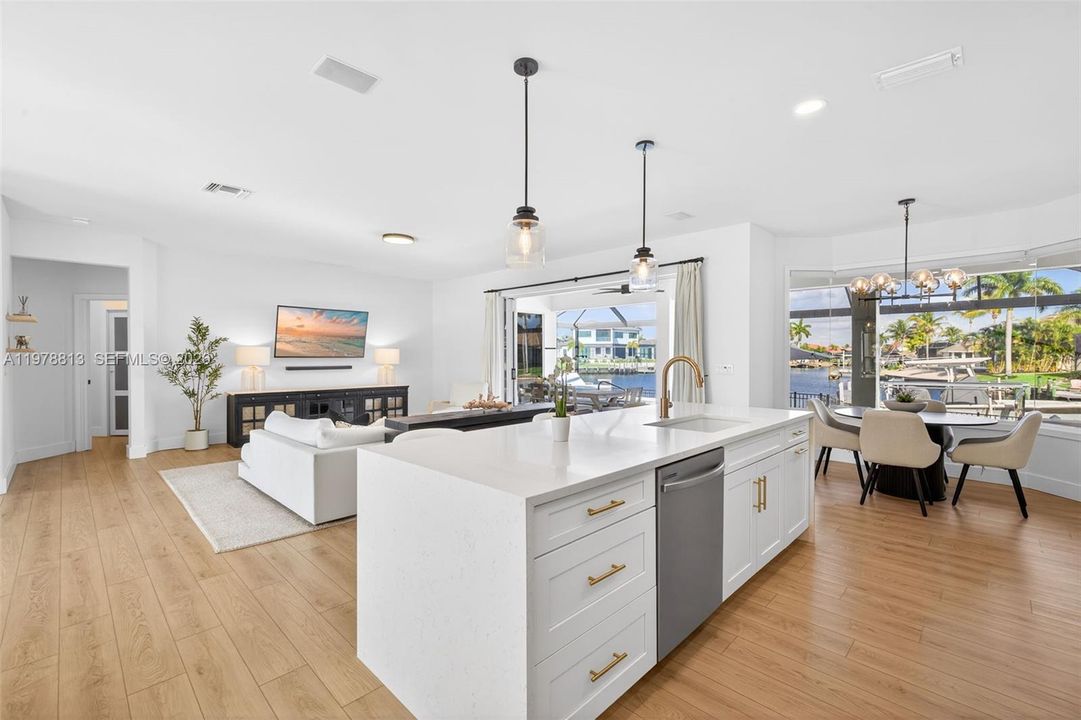 Kitchen with new white cabinetry, open floor plan, light stone quartz countertops, a 9' center island with sink, and hanging lights, & recessed lighting