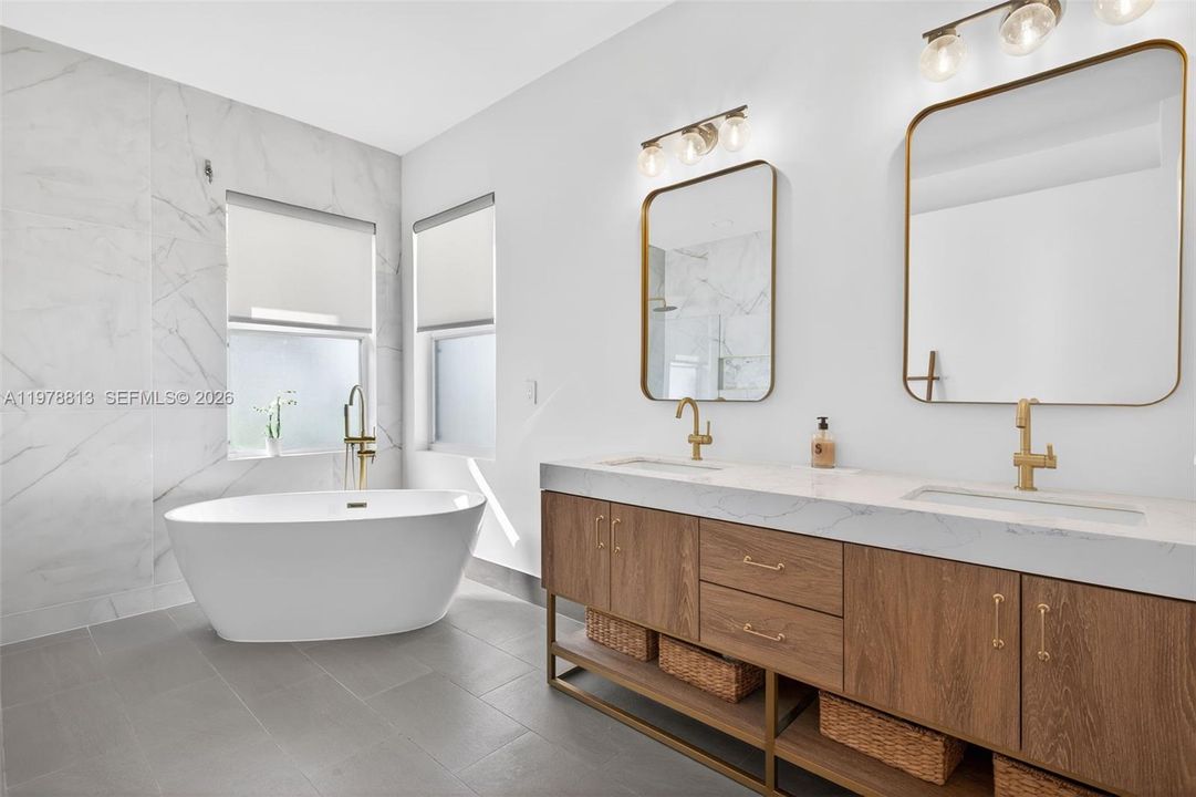 Primary bathroom featuring double vanity, a freestanding tub, and 36' tile walls