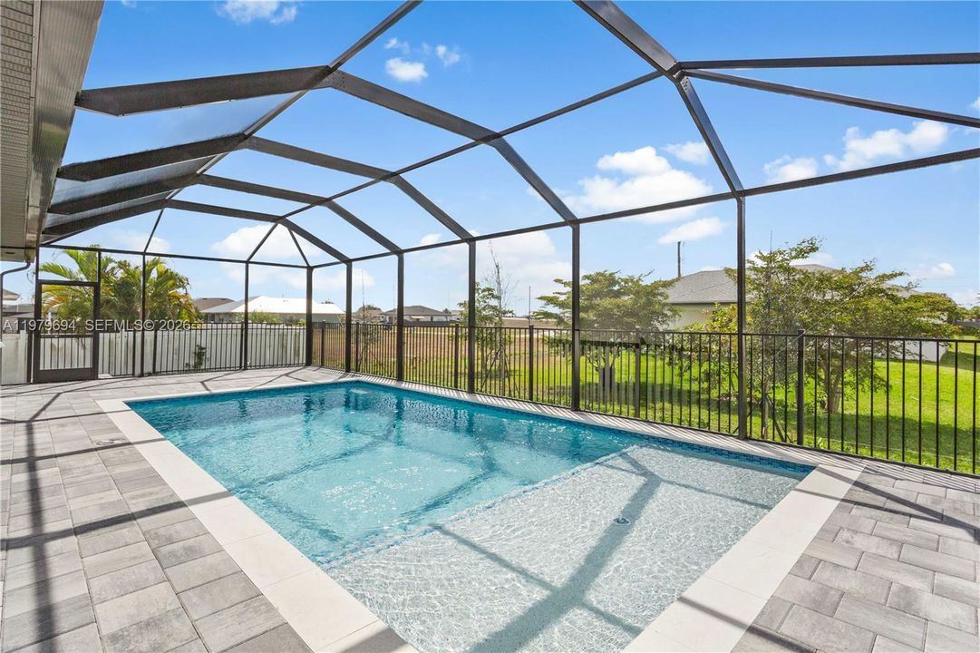 Step outside to SCREENED LANAI w/ SALTWATER POOL, landscaped surrounding & FULLY EQUIPED OUTDOOR KITCHEN w/ BUILT-IN stainless steel BBQ GRILL, SINK, BEVERAGE REFRIGERATOR, GRANITE COUNTERTOPS & MODERN BACKSPLASH, ideal for OUTDOOR DINING & ENTERTAINING