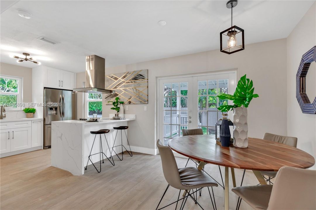 Open-concept dining and kitchen with breakfast bar and backyard access