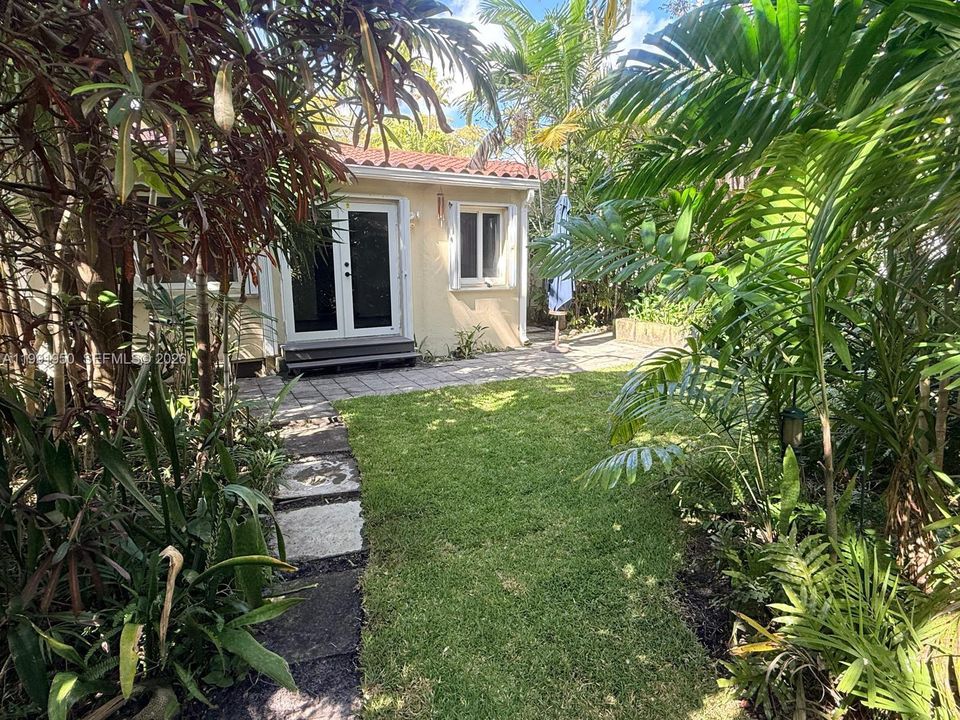 Lush fenced yard with mature palms and natural shade