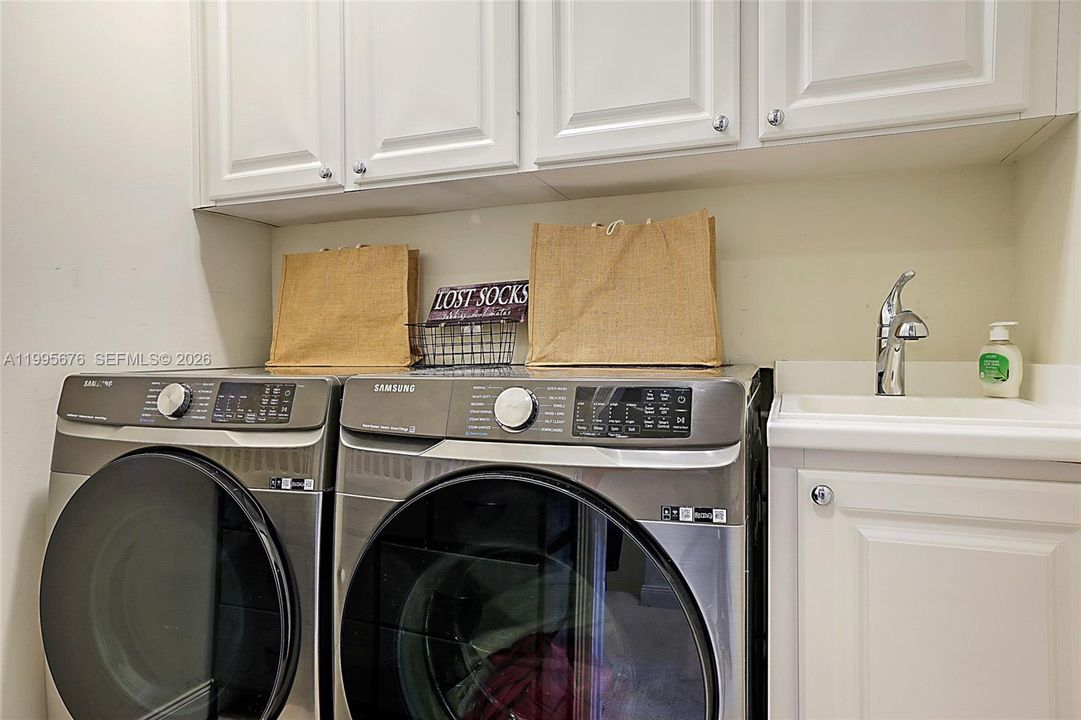 Laundry room with sink and cabinet storage.