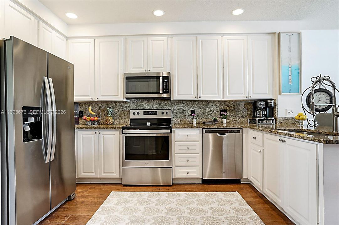 Stainless steel appliances/granite countertops with counter seating.