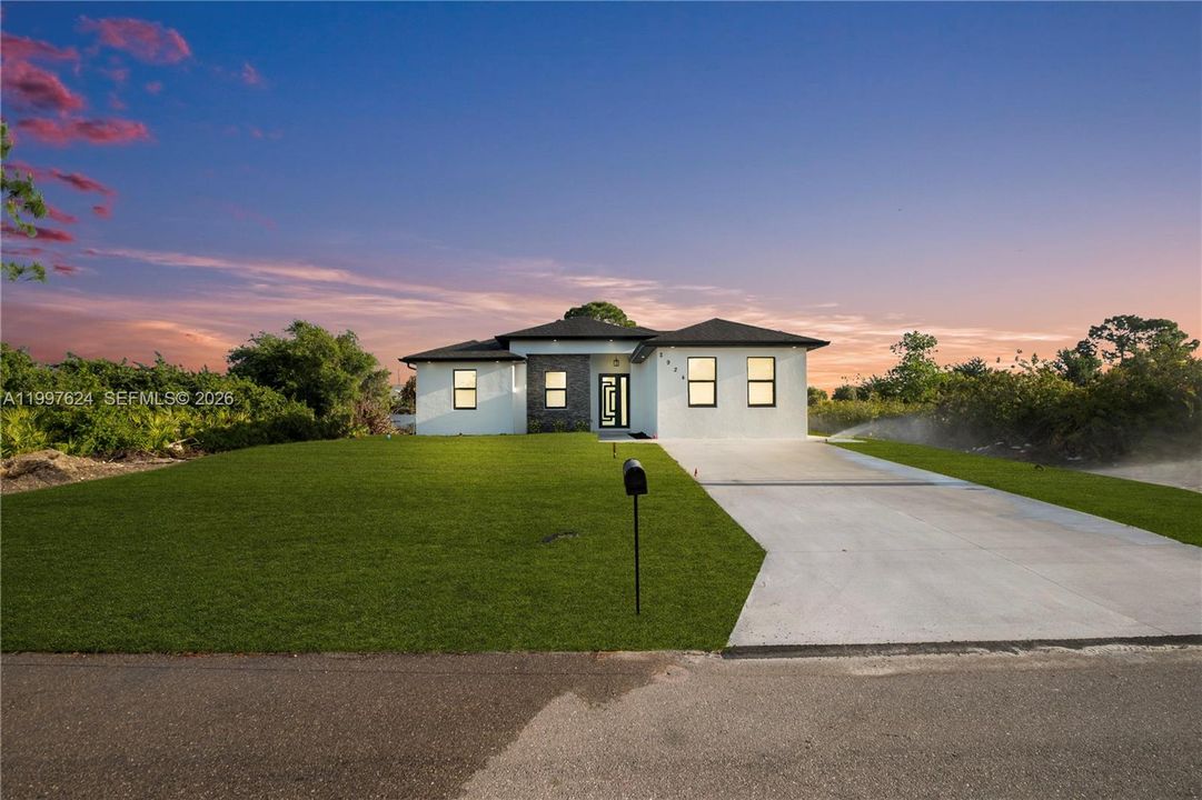 View of front of house with driveway, a yard, stucco siding, and stone siding