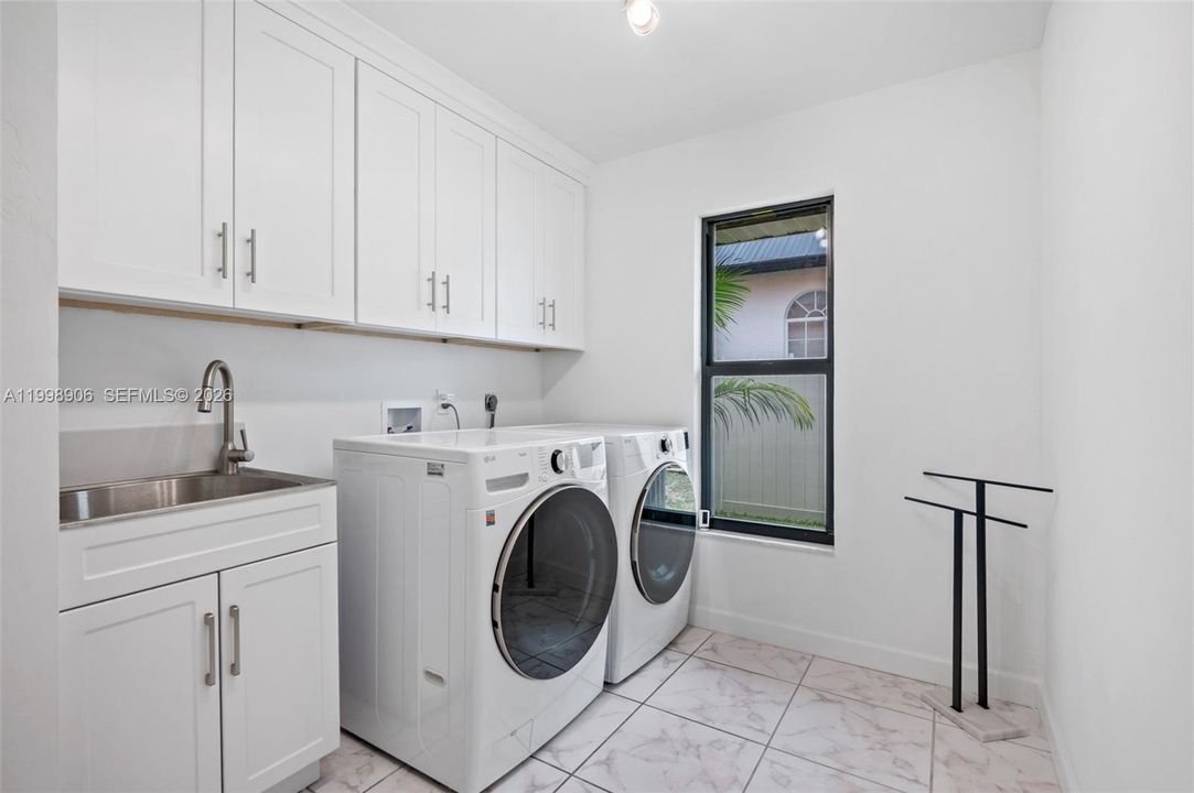Huge Indoor laundry room with lots of cabinets and laundry sink