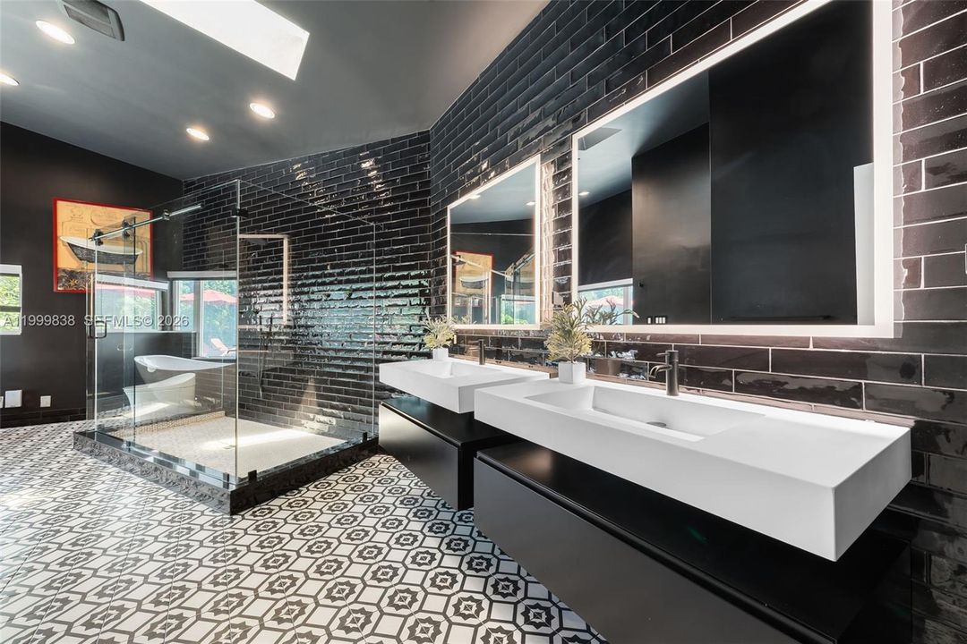 Primary en suite bath featuring dual sinks, back lit mirrors & custom oversized steam shower with seamless glass enclosure.