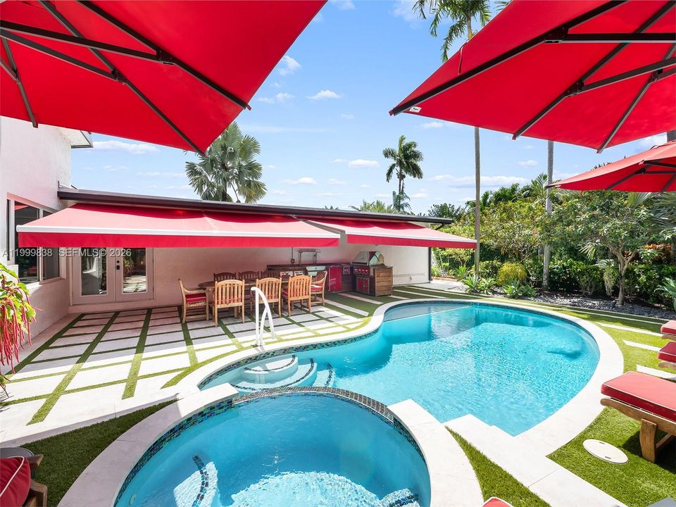 Resort style salt water pool featuring summer kitchen and retractable awnings