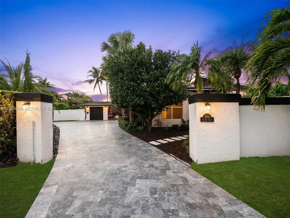 Twilight privacy wall featuring expansive driveway. Second entrance