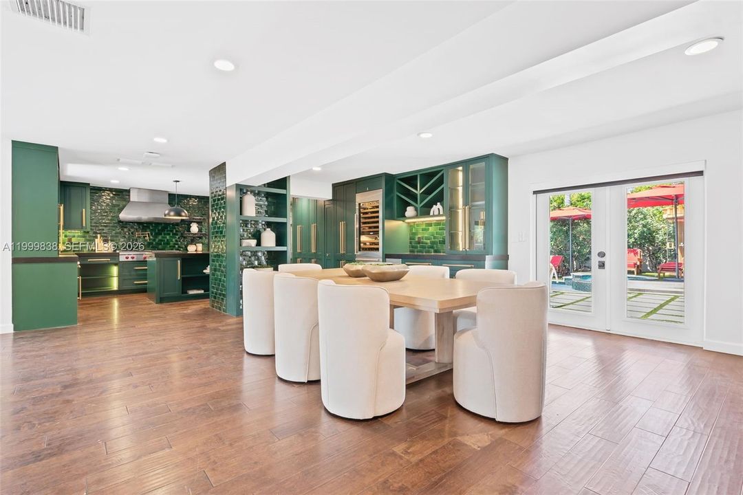 View of dining area into expansive custom chefs kitchen. Double doors lead to outdoor oasis