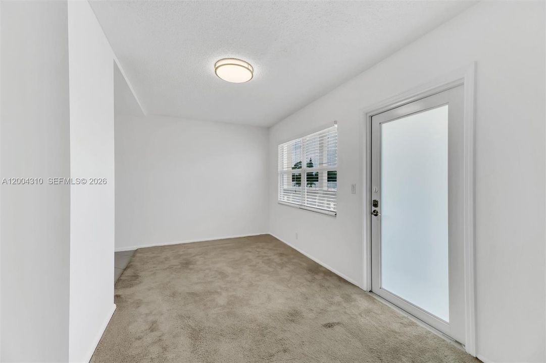 Dining area / entry zone — separate alcove space with window and porch door, updated ceiling fixture