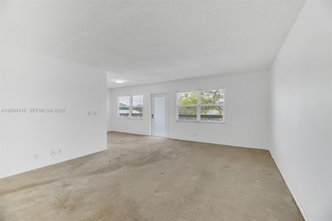 Living room — bright, spacious, door to porch visible, windows with natural light