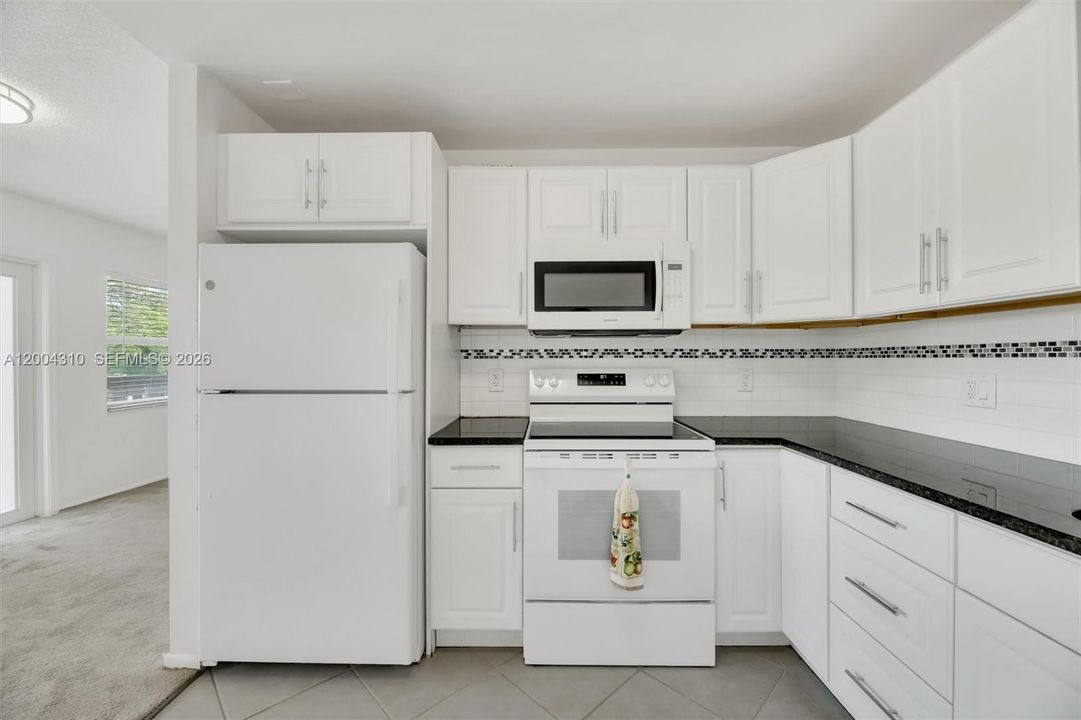Kitchen close-up — refrigerator, range, over-range microwave, cabinetry detail