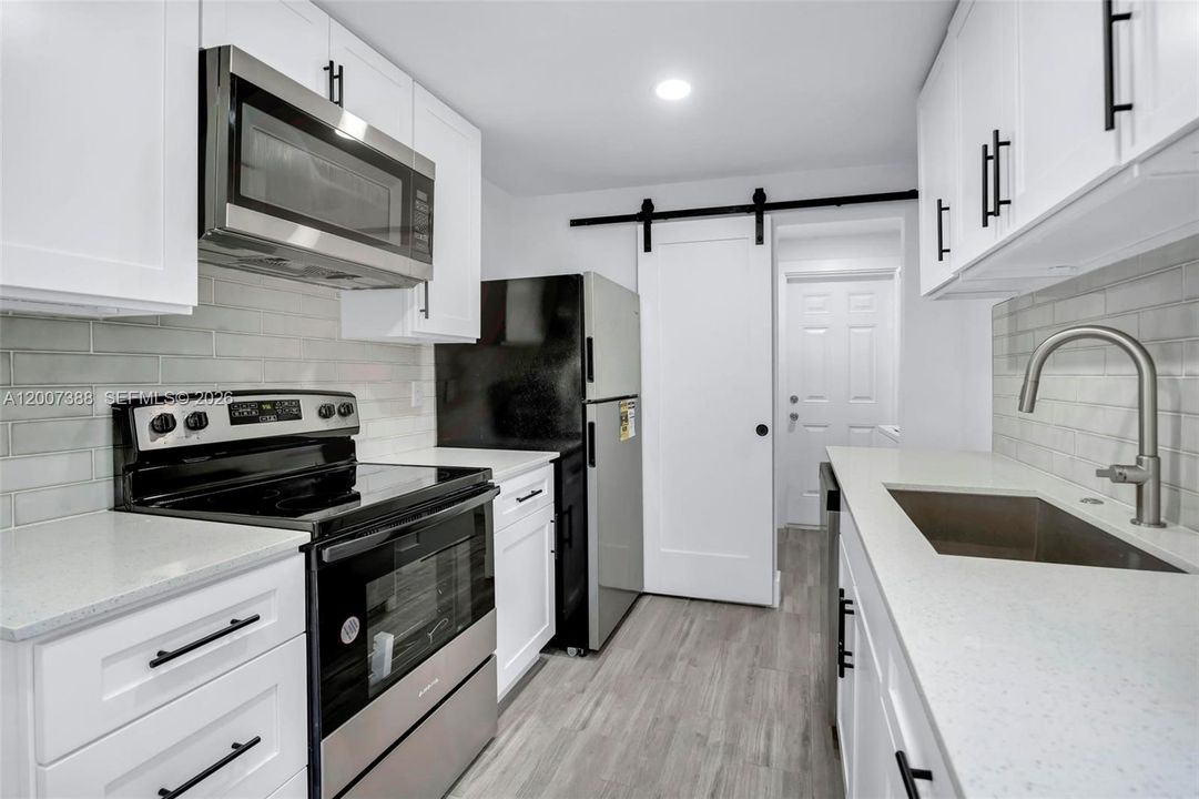 Kitchen leading into storage and laundry