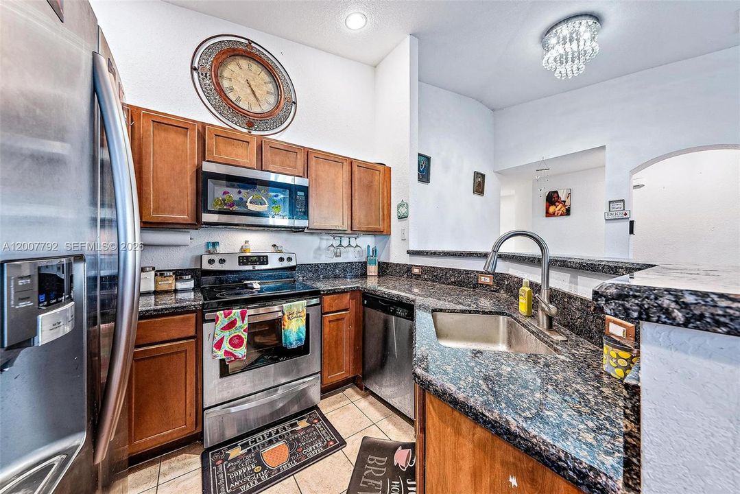 Open Kitchen with granite countertops, breakfast bar and stainless-steel appliances. Vaulted ceilings and tile flooring.