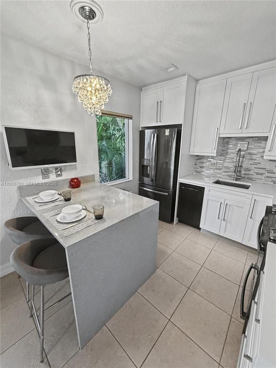 Modern white kitchen with stainless appliances, center island, and breakfast bar seating